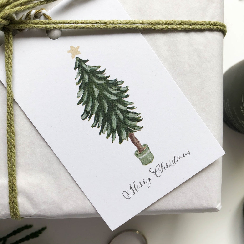 hand illustrated merry christmas tree tags on gift wrapped box close up