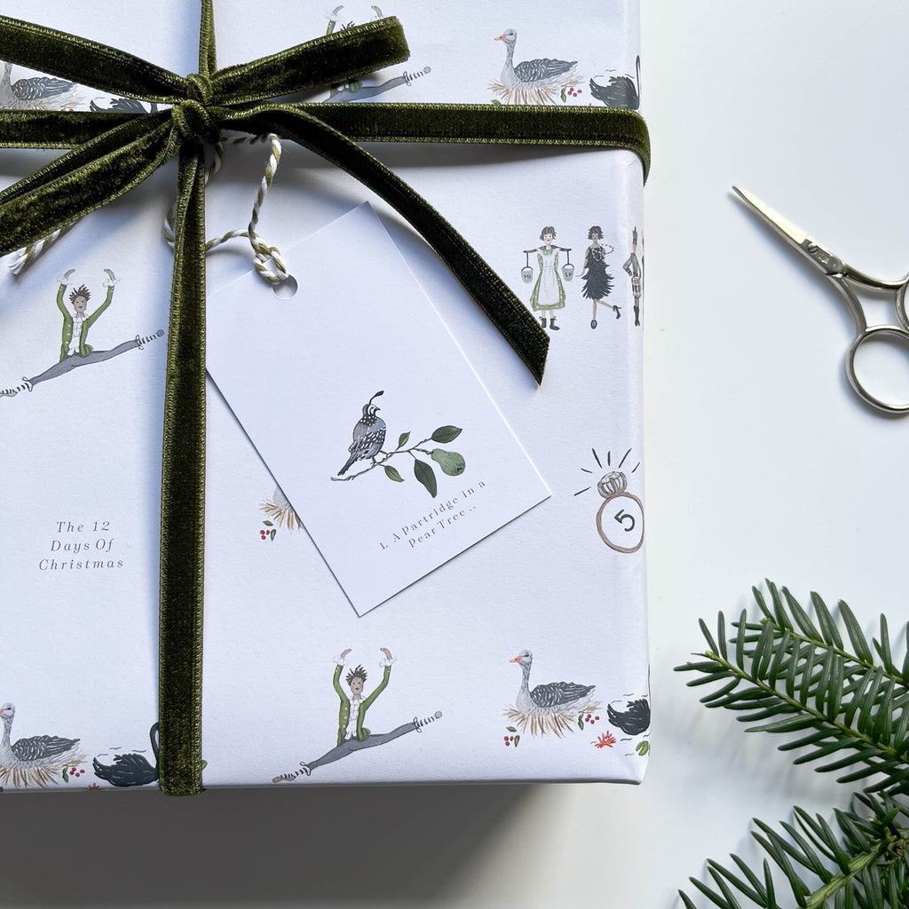 12 days of christmas gift tags with hand illustrated a partridge in a pear tree gift tags on gift wrapped parcel & winter foliage