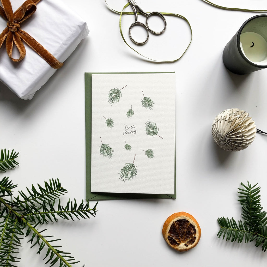 falling pine christmas card on table with gift wrap & pine branches